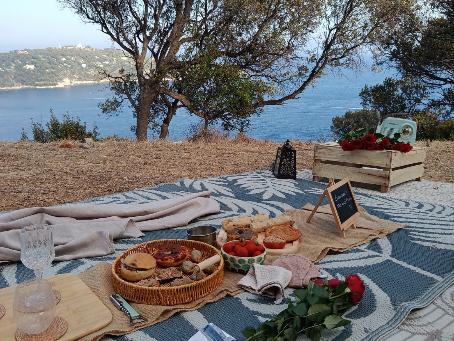 Picnic spread with red roses and The Nice Picnic chalkboard sign