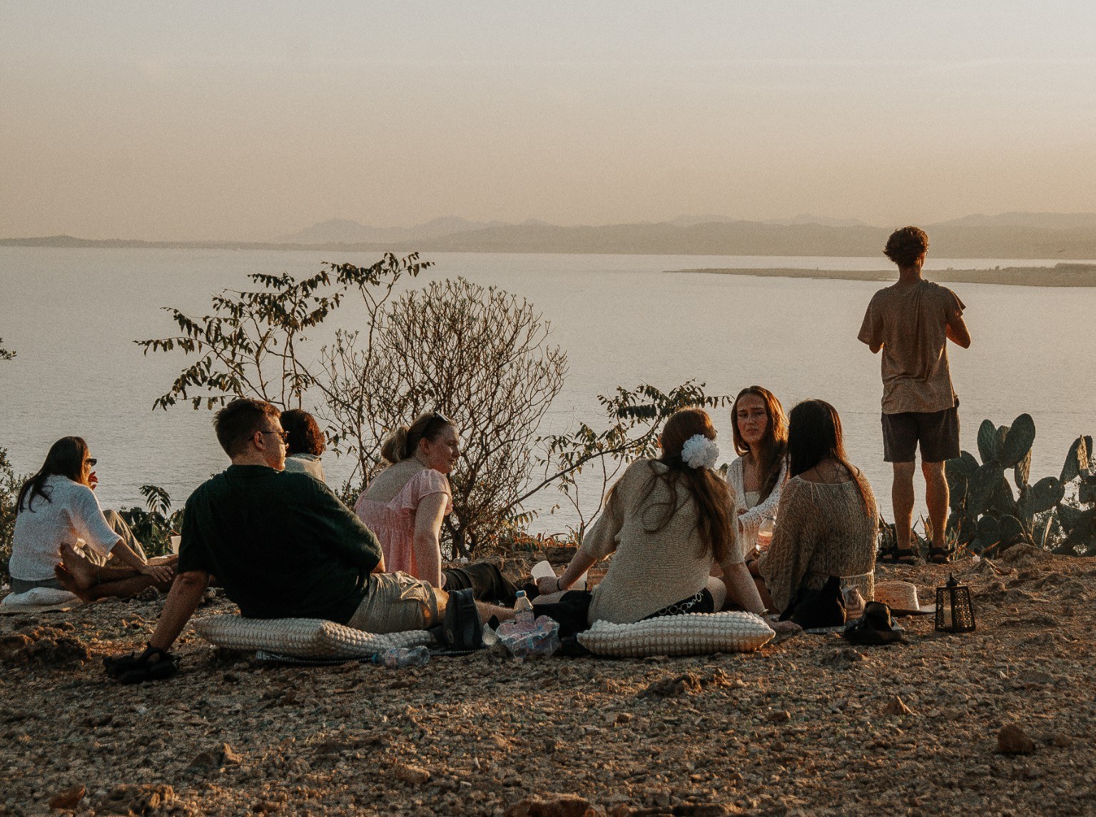Guests gathered on cushions at dusk above the Mediterranean